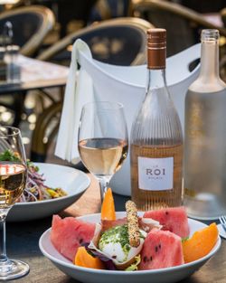 Plat avec melon, pastèque et mozzarella accompagné de vin rosé sur une table en terrasse de brasserie à Brive la Gaillarde.