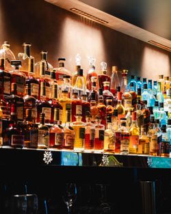 Une sélection variée de bouteilles de boissons alcoolisées alignées sur une étagère éclairée.