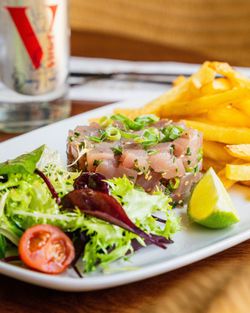 Tartare de poisson accompagné de frites dorées, salade verte et quartier de citron.