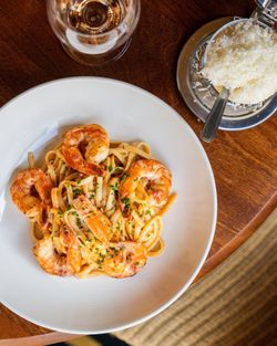 Pâtes aux crevettes, servies avec du fromage et un verre de rosé. Cuisine faite maison au Garden Ice Café.