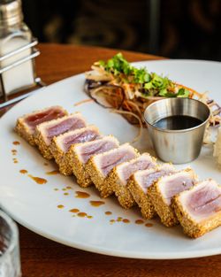 Morceaux de thon saisies en croûte de sésame, accompagnés de salade et sauce.