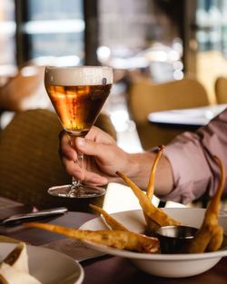 Une bière servie dans un verre élégant, accompagnée de mets appétissants dans un cadre convivial.