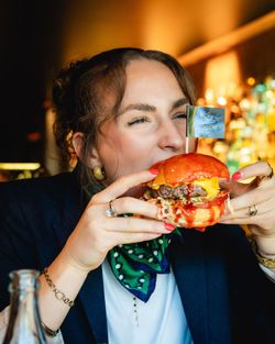 Femme en train de manger un hamburger avec sauce et fromage dans un restaurant à Brive la Gaillarde.