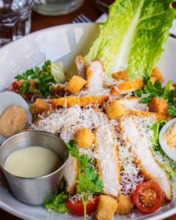 Une salade composée avec du poulet, des tomates, de la laitue et une sauce onctueuse.