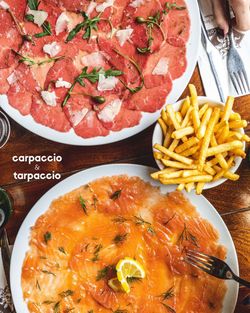 Carpaccio de viande et saumon fumé avec frites, présenté sur une table en bois dans une brasserie à Brive-la-Gaillarde.