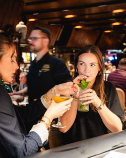 Deux femmes dégustent des cocktails dans une ambiance chaleureuse typique d'une brasserie à Brive-la-Gaillarde.