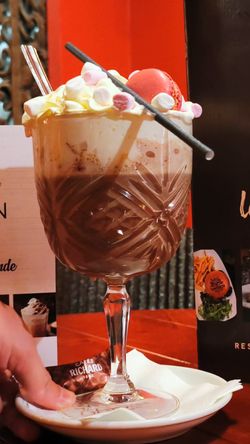 Boisson chocolatée avec chantilly, mini guimauves et macaron rouge dans un verre à pied au Garden ice café.