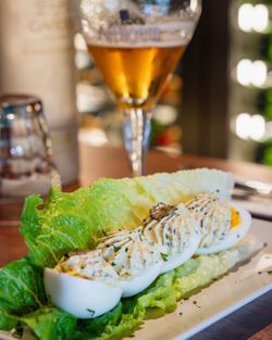 Oeufs farcis nappés de sauce aux herbes, servis sur un lit de laitue verte fraîche en brasserie terrasse.