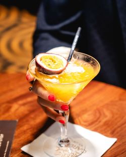 Cocktail jaune avec fruit de la passion et paille noire, servi au Garden Ice Café Périgueux sur une table en bois.
