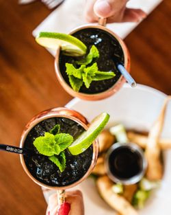Deux cocktails avec glace pilée, menthe et tranche de citron vert, servis dans des verres en cuivre à la brasserie terrasse.