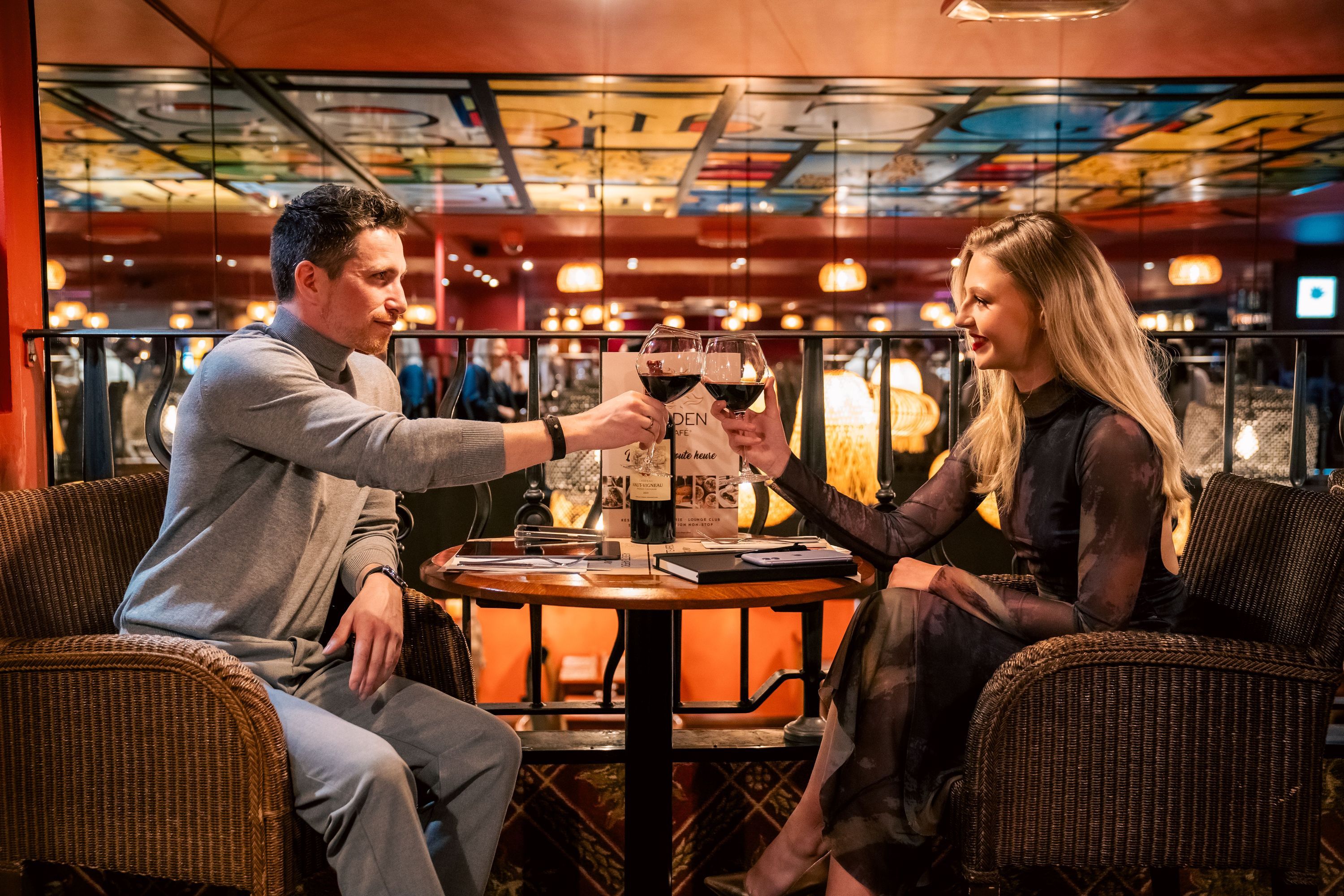 Couple trinque avec des verres de vin dans une brasserie moderne, terrasse accueillante à Brive la Gaillarde.