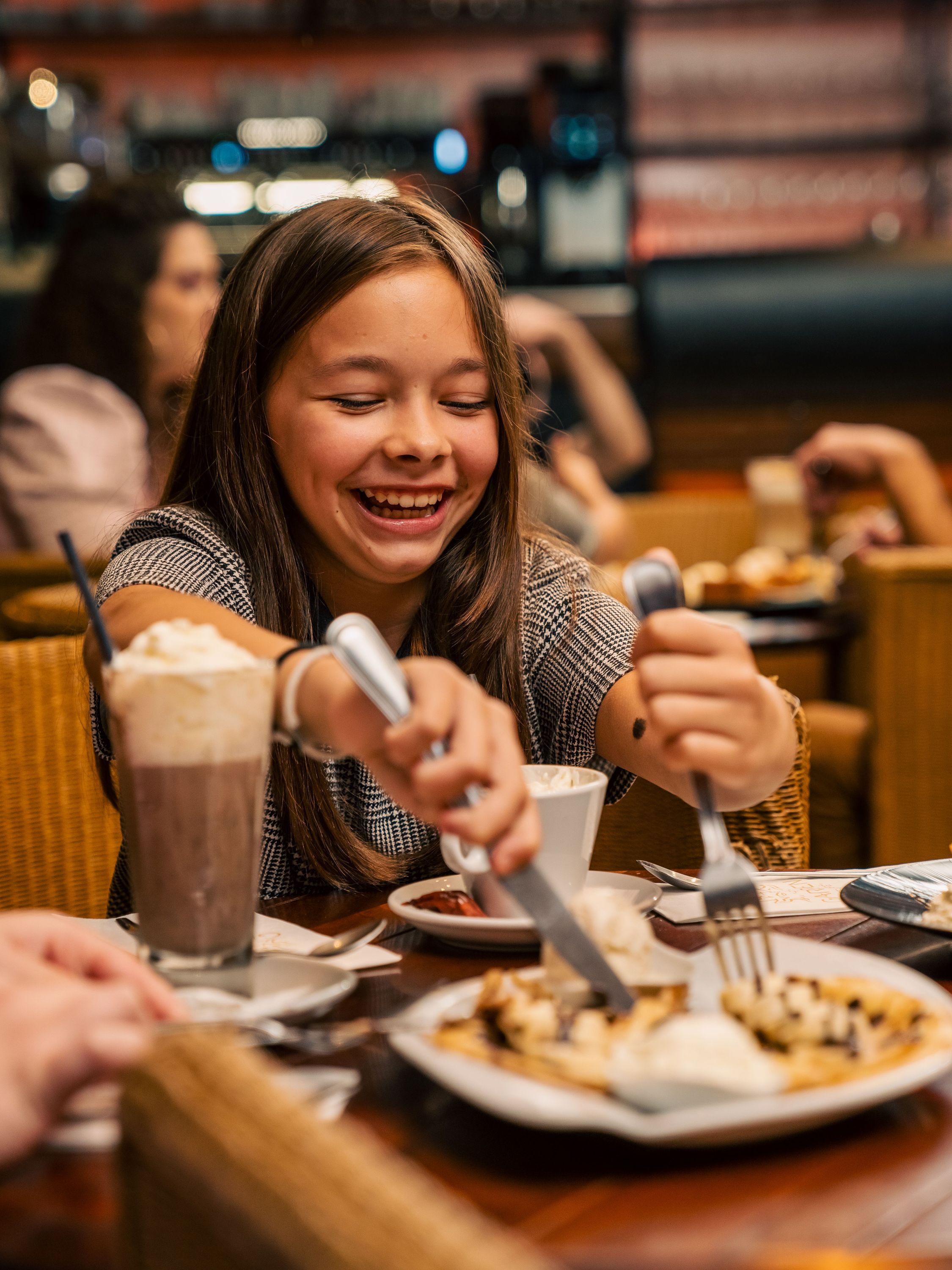 Une jeune fille déguste un dessert avec enthousiasme au Garden Ice Café, un restaurant à Brive-la-Gaillarde.