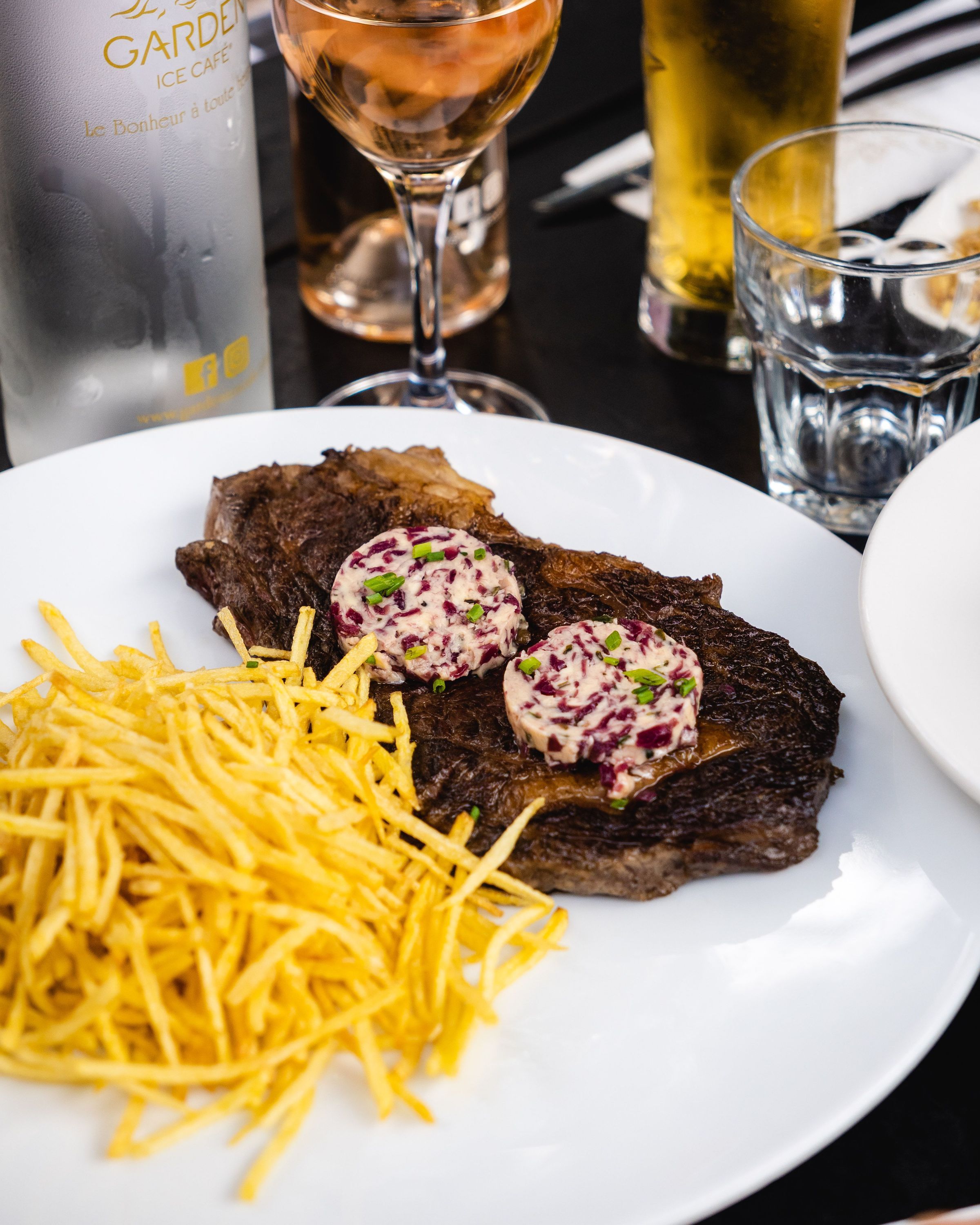 Steak avec sauce, servi avec frites croustillantes, accompagné de boissons au Garden Ice Café.