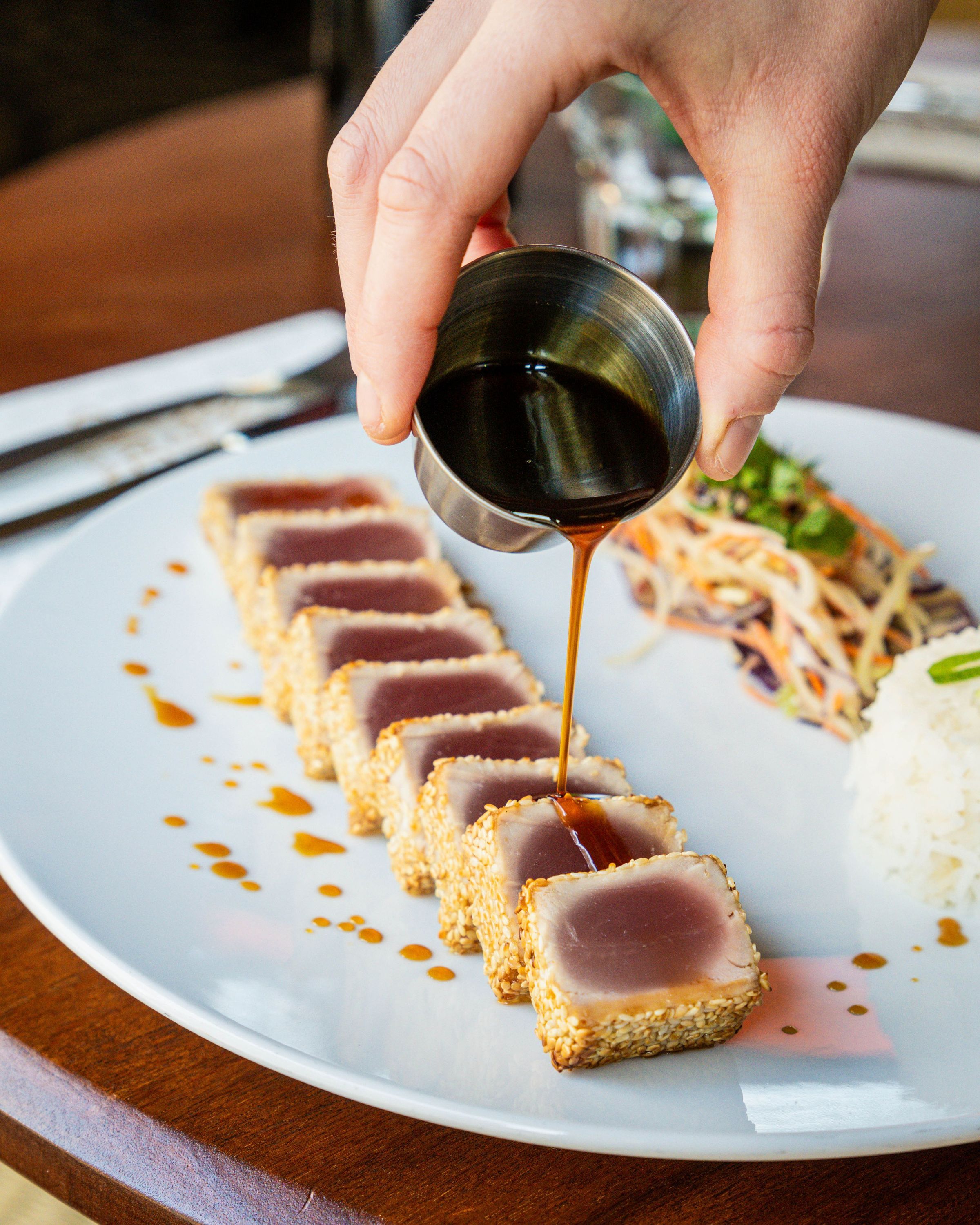 Tartare de thon avec sauce, servi avec du riz et une salade, dans un restaurant qui propose une cuisine faite maison.