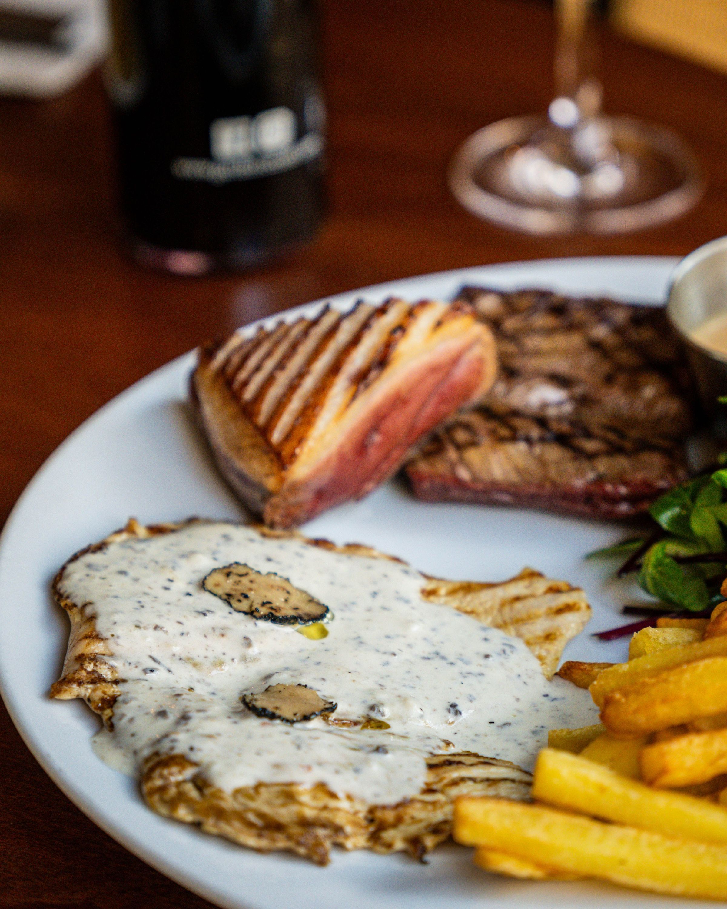 Plat principal avec poisson, viande, sauce et frites à la Garden Ice Café.
