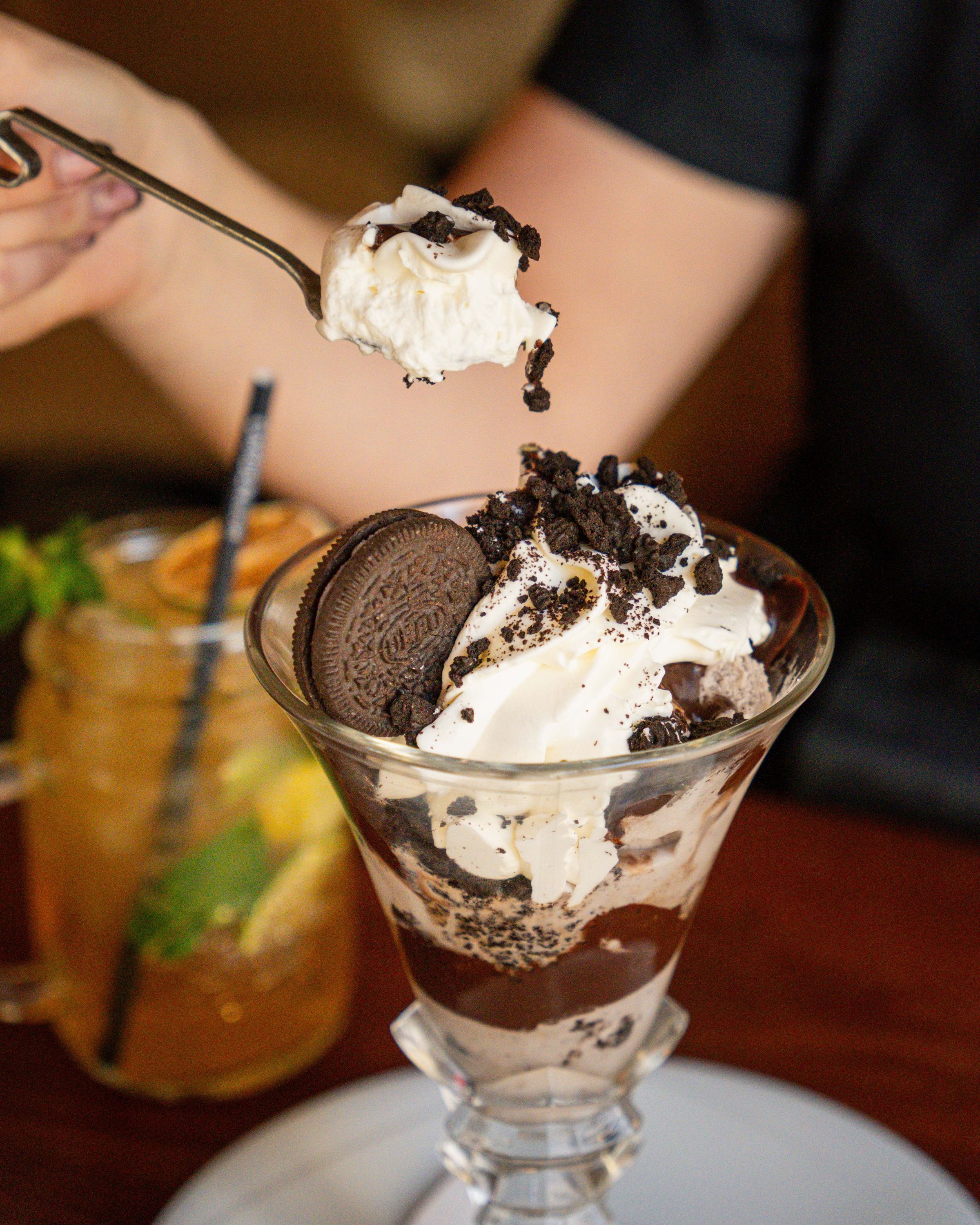 Un dessert glacé avec crème chantilly, morceaux de biscuit Oreo et sauce chocolat.
