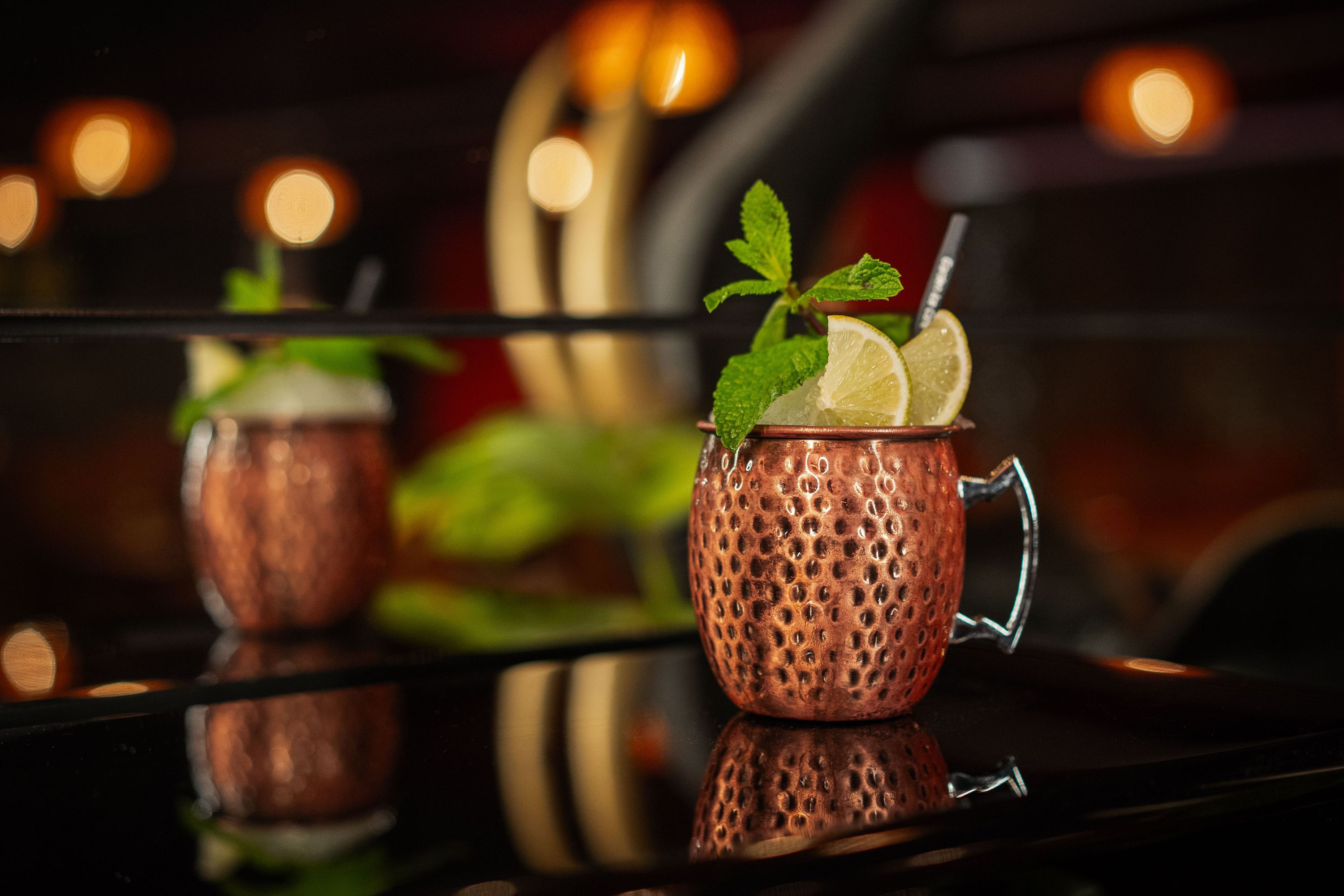 Cocktail frais dans un verre en cuivre, décoré de menthe et de quartiers de citron. Terrasse de la brasserie.