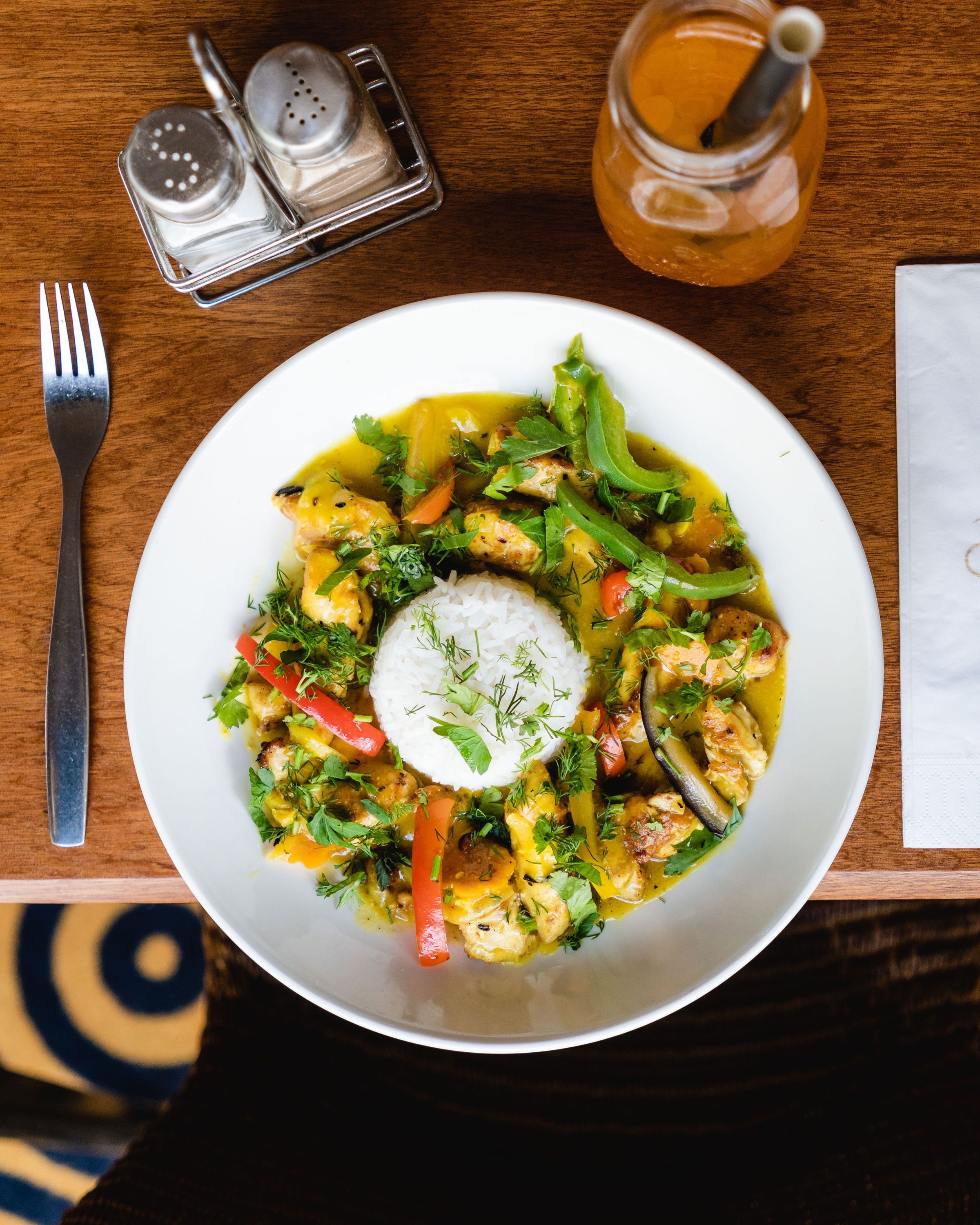 Plat coloré avec du riz, légumes et herbes, accompagné d'une boisson au café.