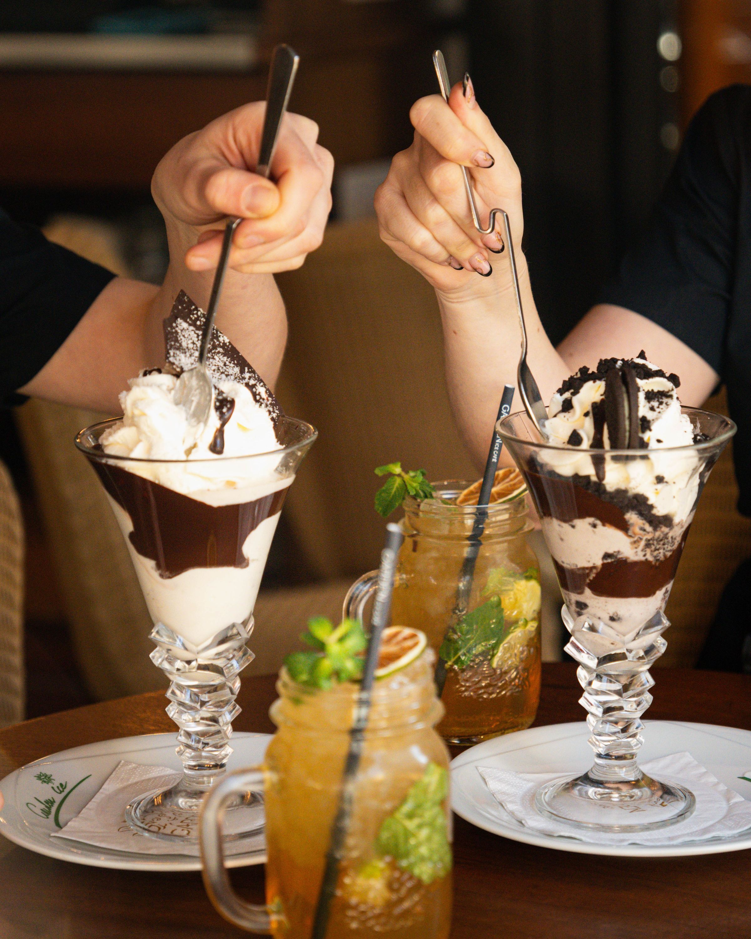 Desserts glacés servis dans des coupes élégantes, avec sauce chocolat et garnitures.