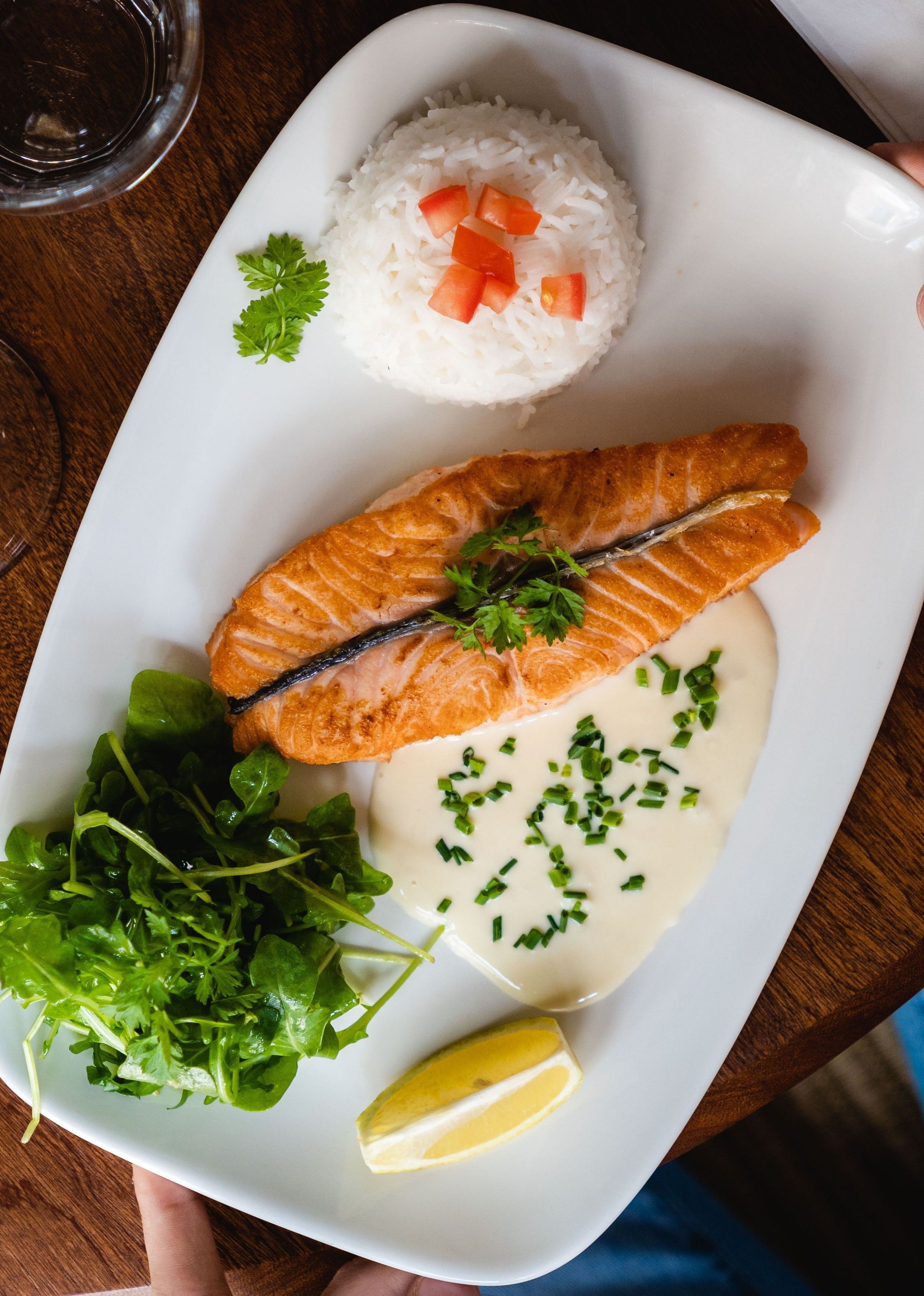Poisson grillé avec riz, sauce crémeuse, salade verte et quartier de citron.